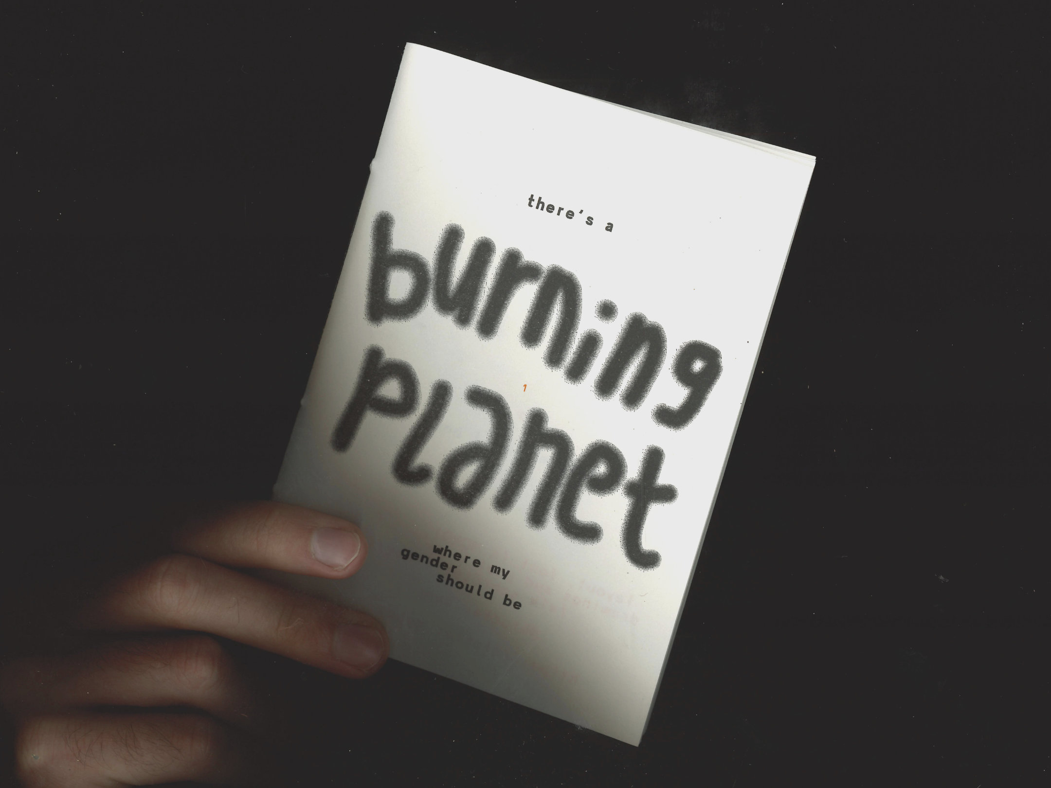 hand holding zine cover: “there’s a burning planet where my gender should be”