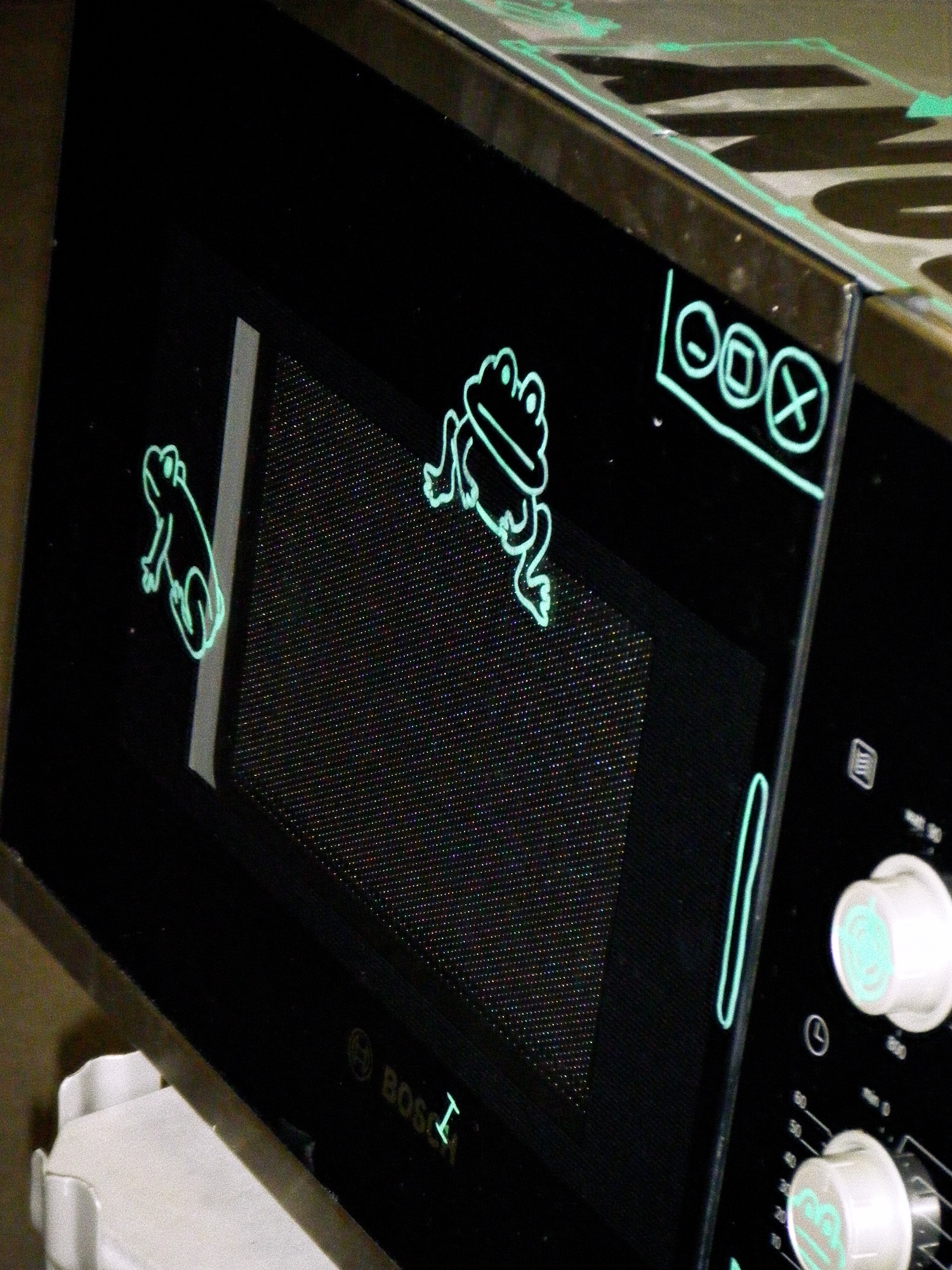 the front of the microwave with two frogs drawn on it, as well as parts of a computer interface.